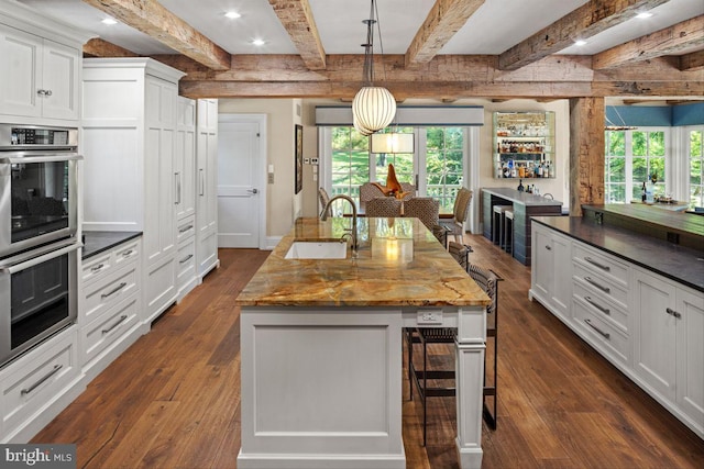 720 Swedesford Rd, Lower Gwynedd, PA 19002 - kitchen with a sink, stainless steel double oven, dark wood-style floors, beam ceiling, and a breakfast bar area