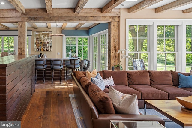 living room featuring a wealth of natural light, beamed ceiling, and dark hardwood / wood-style flooring