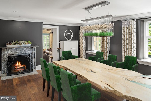 dining space featuring hardwood / wood-style floors, crown molding, and a fireplace