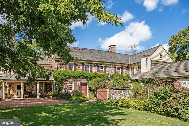 720 Swedesford Rd, Lower Gwynedd, PA 19002 - rear view of property with stone siding, a lawn, and a chimney