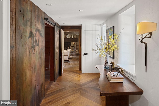 corridor with a barn door and parquet flooring