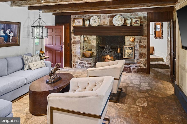 living room featuring beamed ceiling, a notable chandelier, and a fireplace