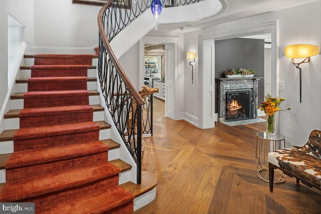 stairway featuring a premium fireplace and parquet floors