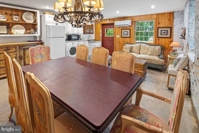 dining area featuring a notable chandelier, wood walls, sink, independent washer and dryer, and a wall mounted air conditioner