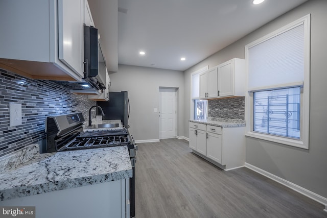 1823 N Caroline St, Baltimore, MD 21213 - kitchen featuring appliances with stainless steel finishes, tasteful backsplash, light wood-style floors, baseboards, and white cabinets