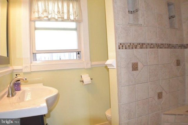 bathroom with vanity, toilet, and a tile shower