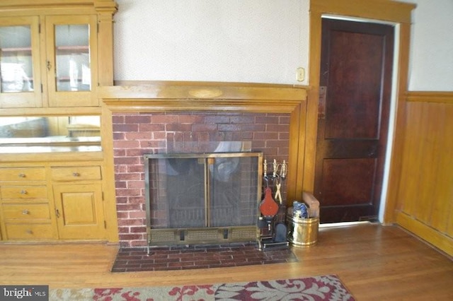 details featuring a brick fireplace, wood walls, and hardwood / wood-style flooring