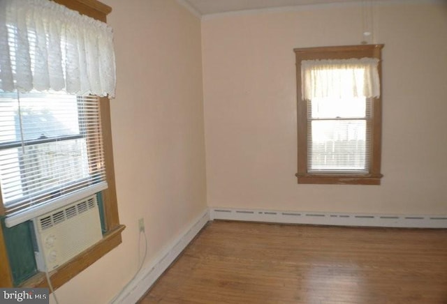 unfurnished room featuring wood-type flooring and a baseboard heating unit