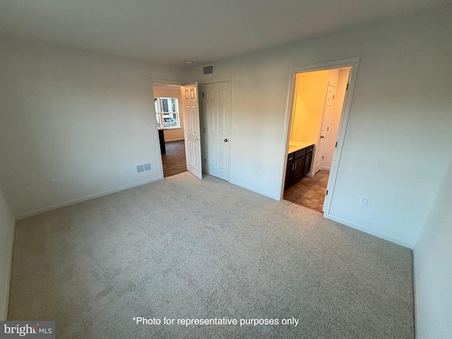 unfurnished bedroom featuring connected bathroom and light hardwood / wood-style flooring