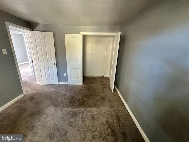 unfurnished bedroom with dark carpet and a closet