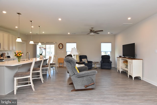 living room featuring ceiling fan, sink, and light hardwood / wood-style floors