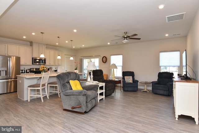 living room featuring light hardwood / wood-style flooring, a healthy amount of sunlight, and ceiling fan