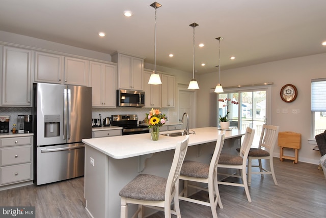 kitchen featuring a center island with sink, sink, decorative backsplash, and appliances with stainless steel finishes