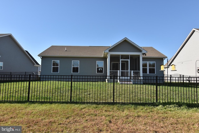 rear view of house featuring a sunroom and a yard