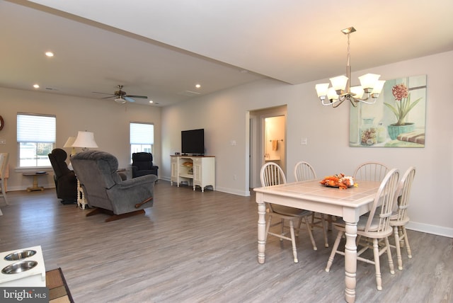 dining space with wood-type flooring and ceiling fan with notable chandelier