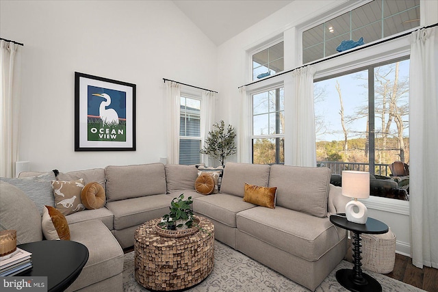 living room featuring vaulted ceiling, baseboards, and wood finished floors