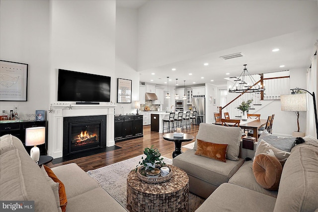 living area featuring visible vents, a fireplace with flush hearth, stairway, dark wood-type flooring, and recessed lighting