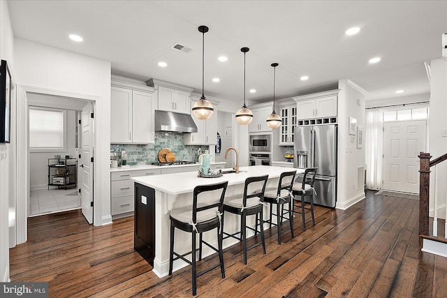 kitchen featuring under cabinet range hood, dark wood-style flooring, visible vents, light countertops, and appliances with stainless steel finishes