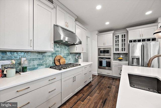 kitchen with dark wood finished floors, appliances with stainless steel finishes, light countertops, under cabinet range hood, and white cabinetry