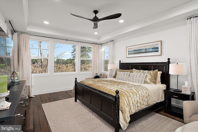 bedroom with dark wood finished floors, a raised ceiling, crown molding, and recessed lighting