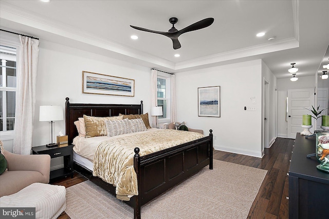 bedroom featuring baseboards, dark wood-style floors, ornamental molding, a tray ceiling, and recessed lighting