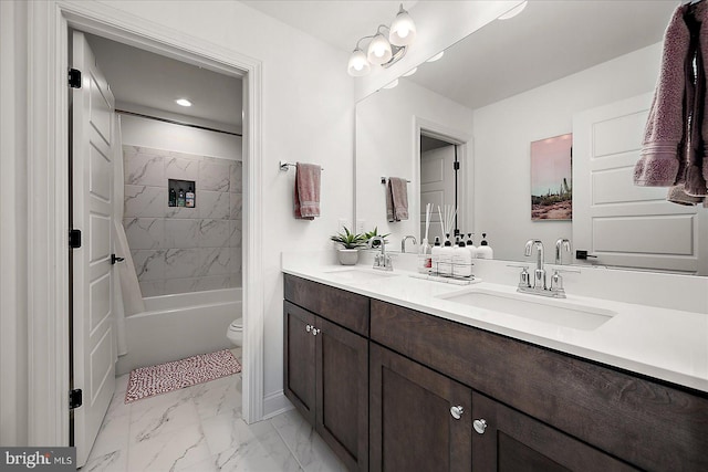 full bath with toilet, marble finish floor, double vanity, and a sink