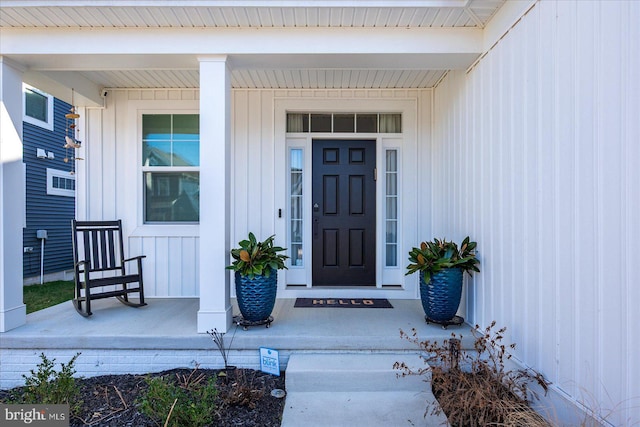 property entrance featuring covered porch and board and batten siding