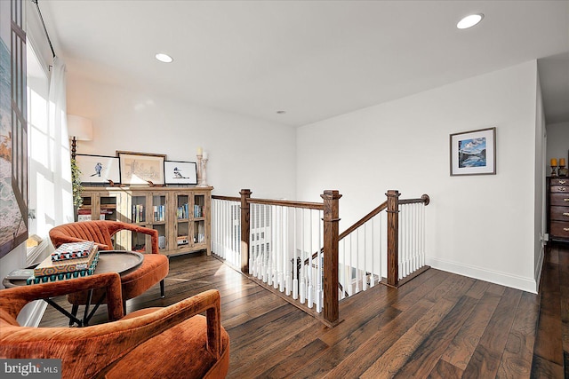 sitting room with baseboards, dark wood-type flooring, an upstairs landing, and recessed lighting