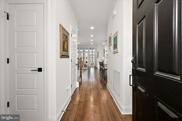 hallway featuring dark wood finished floors, crown molding, recessed lighting, visible vents, and baseboards