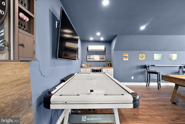 recreation room featuring recessed lighting, a wall unit AC, baseboards, and wood finished floors