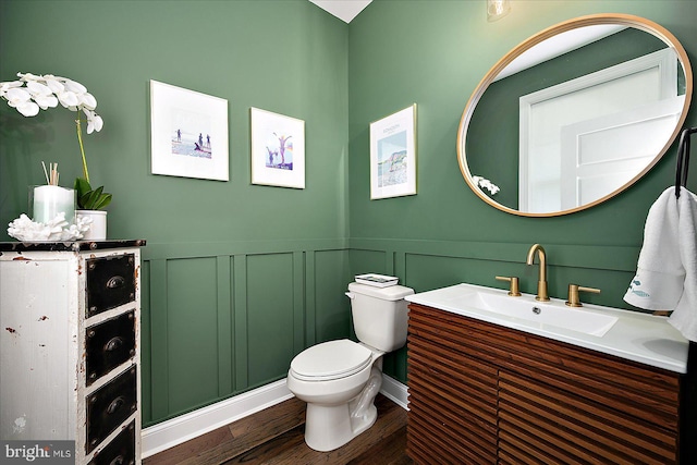 bathroom featuring toilet, vanity, wood finished floors, and wainscoting