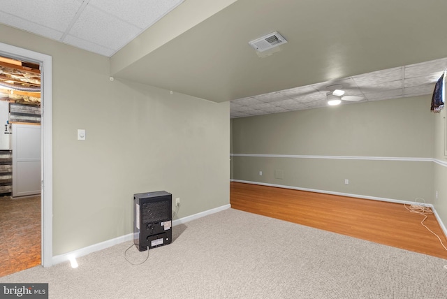 basement featuring heating unit, carpet, and a drop ceiling