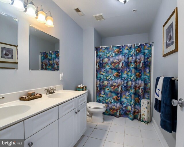 bathroom with tile patterned flooring, vanity, toilet, and walk in shower