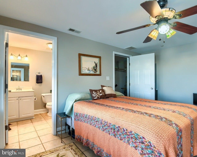 bedroom featuring ensuite bathroom, ceiling fan, sink, light tile patterned floors, and a closet