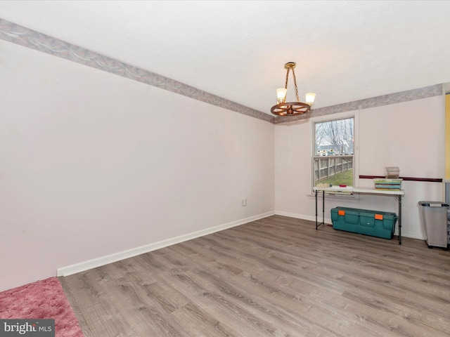 empty room featuring an inviting chandelier and light hardwood / wood-style flooring