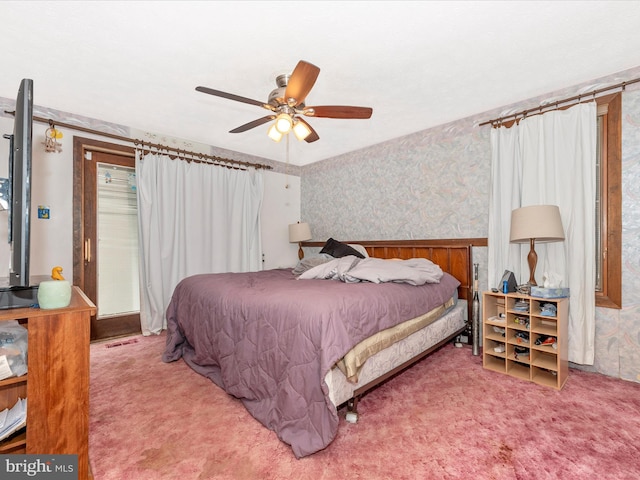 carpeted bedroom featuring wood walls and ceiling fan