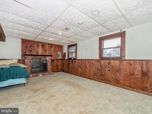 unfurnished bedroom featuring light colored carpet, a fireplace, and wooden walls