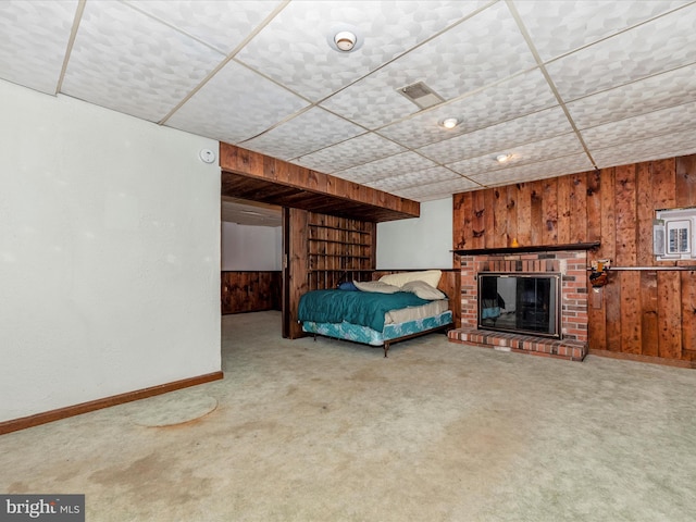 unfurnished bedroom featuring wooden walls, carpet, and a brick fireplace