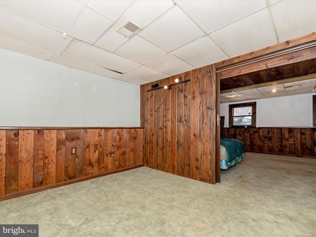 basement featuring light colored carpet and wooden walls