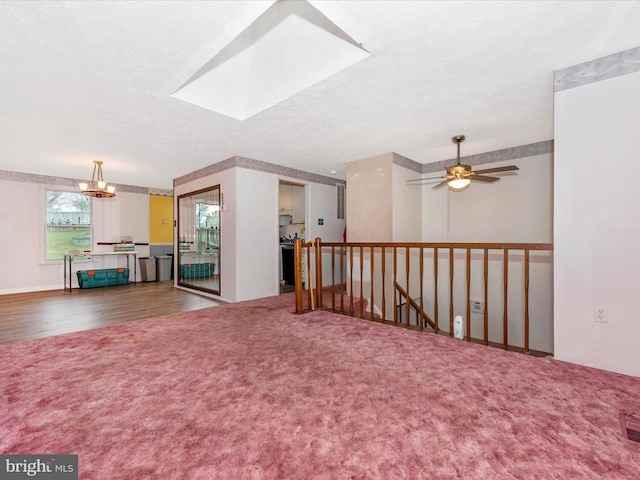 carpeted spare room with ceiling fan with notable chandelier and a textured ceiling