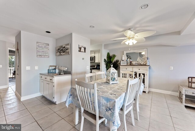 dining space featuring ceiling fan, light tile patterned floors, and sink