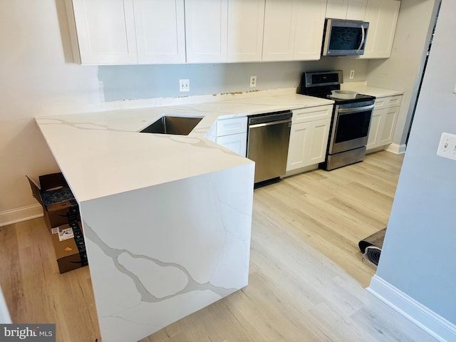 401 Bay Shore Dr Unit 2A, Barnegat, NJ 08005 - kitchen with stainless steel appliances, a peninsula, white cabinetry, light wood-style floors, and baseboards