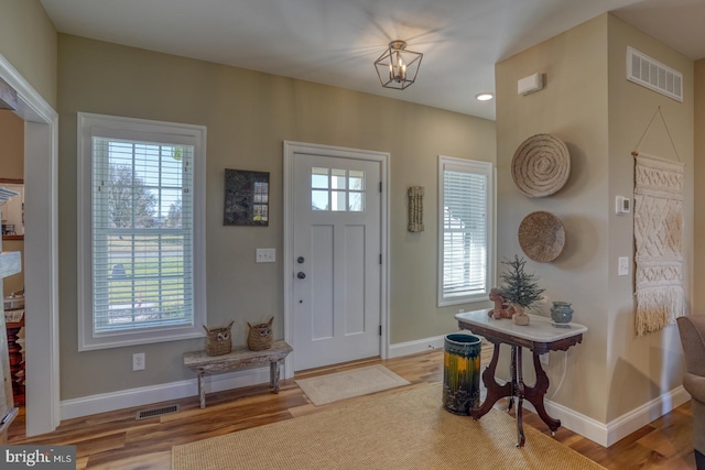 entryway with hardwood / wood-style floors, a healthy amount of sunlight, and a chandelier