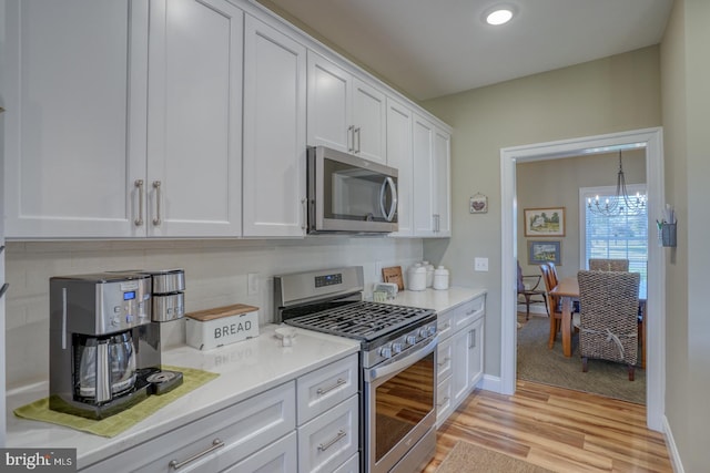 kitchen featuring a chandelier, white cabinetry, light hardwood / wood-style flooring, and appliances with stainless steel finishes