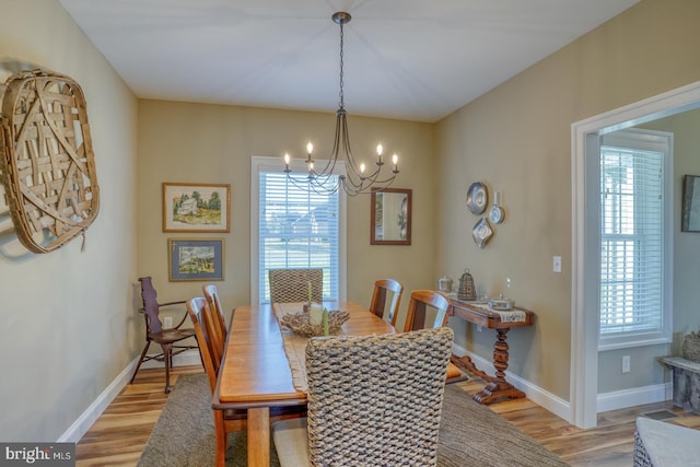 dining area with light wood-type flooring and a notable chandelier