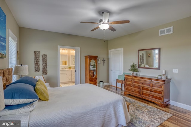 bedroom featuring connected bathroom, light wood-type flooring, multiple windows, and ceiling fan