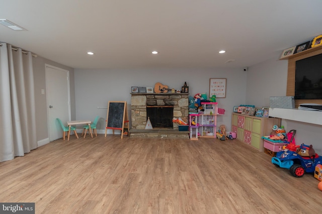 game room featuring light wood-type flooring and a fireplace