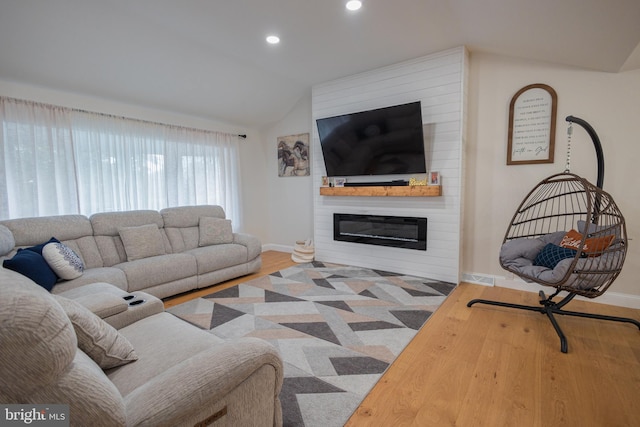 living room featuring a large fireplace, hardwood / wood-style flooring, and vaulted ceiling