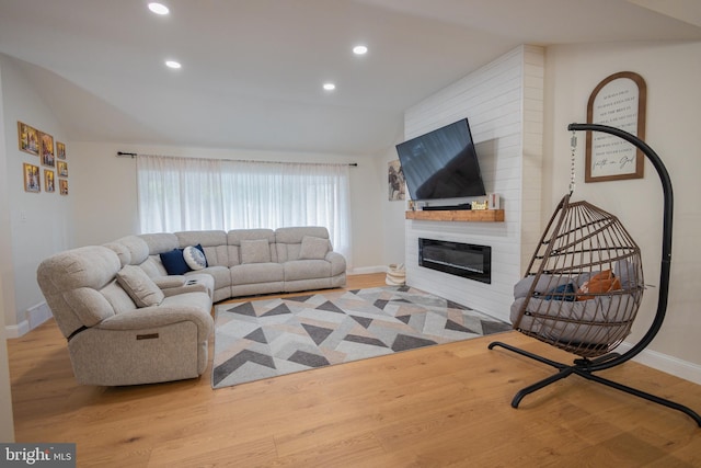 living room with light hardwood / wood-style floors, a large fireplace, and lofted ceiling