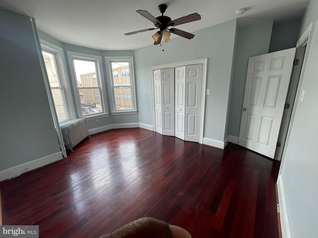 unfurnished bedroom with dark hardwood / wood-style floors, radiator, and ceiling fan